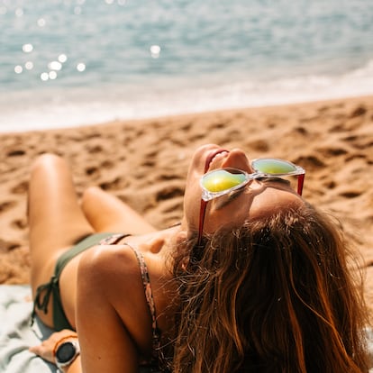 A young woman lies on a towel, sunbathing on a beach in Spain. A lot of copy space