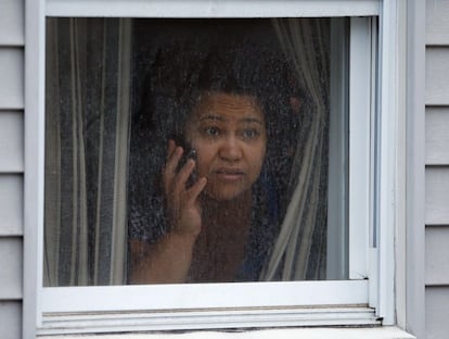 Una mujer mira por la ventana de su casa durante la busqueda policial de uno de los terrorista en la localidad de West (Massachusetts). El tr&aacute;fico de la localidad est&aacute; cortado y las tiendas cerradas.