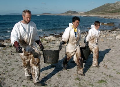 Voluntarios en la playa de Carnota, el 12 de octubre de 2004. Los voluntarios Suen Schwebsch, de Alemania, Carla Franña, de Natal (Brasil) y Deborah Cervone, de Filadelfia (EEUU), (de izq a der) recogen el fuel que extraen de debajo de las piedras. Todavía algunos voluntarios trabajan, limpiando piedra a piedra, en zonas donde el fuel permaneció oculto cuando se iban a cumplir dos años del accidente del petrolero Prestige, que se hundió frente a la costa española con 77.000 toneladas de fuel. 