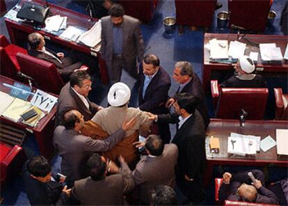 Diputados iraníes tratan de calmar a un legislador conservador durante el conflictivo pleno parlamentario de hoy.