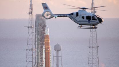 Un helicóptero de la NASA sobrevuela cerca del cohete SLS, durante la cuenta atrás.