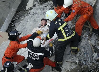 Al menos 13 personas han muerto y 475 han quedado heridas de diversa consideración en el terremoto de magnitud 6,4 que sacudió el sur de Taiwán la pasada madrugada. En la imagen, personal de rescate ayudan a un niño en un edificio de apartamentos de 17 pisos derrumbado durante el terremoto.