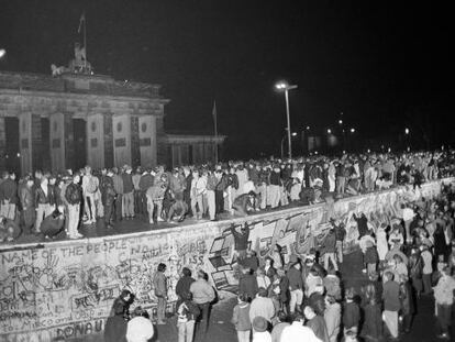 Ciudadanos de Berl&iacute;n Este y Berl&iacute;n Oeste celebran subidos al Muro la apertura de la frontera el 9 de noviembre de 1989