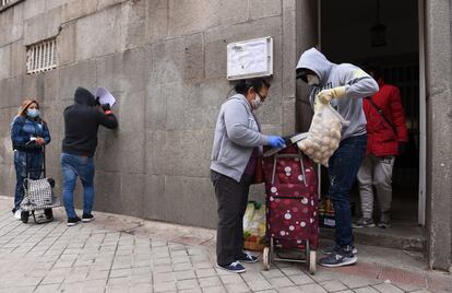 Varias personas acuden a la puerta del banco de alimentos Madrina, en Madrid, donde se ofrece comida a familias necesitadas.