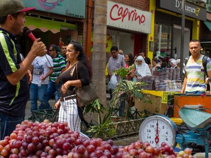 Un vendedor de uvas ambulante ofrece su mercanc&iacute;a con un micr&oacute;fono en una de las calles comerciales de Medell&iacute;n.