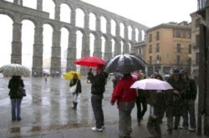 Varios turistas hacen fotograf&iacute;as junto al Acueducto de Segovia mientras nieva en la capital.