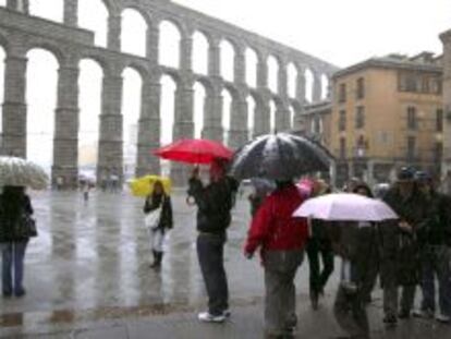 Varios turistas hacen fotograf&iacute;as junto al Acueducto de Segovia mientras nieva en la capital.