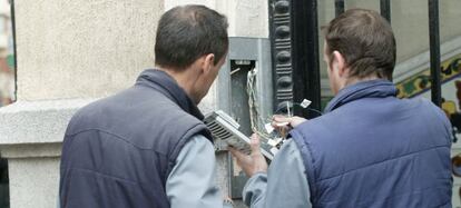 Unos electricistas reparan un portero automático.