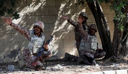 Tres militares paquistaníes se cubren durante el ataque al consulado chino en Karachi (Pakistán).