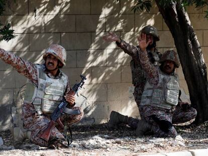 Tres militares paquistaníes se cubren durante el ataque al consulado chino en Karachi (Pakistán).