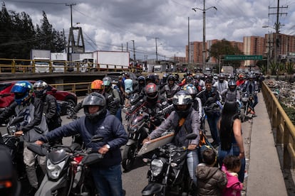 Motociclistas cruzan el bloqueo de la calle 13 llevando sus motos a pie.