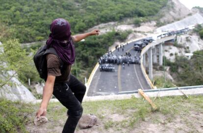 Uno de los manifestantes lanza una piedra a la policía que bloquea el paso de la carretera por donde marchaba la protesta.