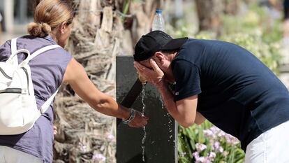 Dos personas se refrescan en una fuente del centro de Valencia en agosto del año pasado durante una de las olas de calor.