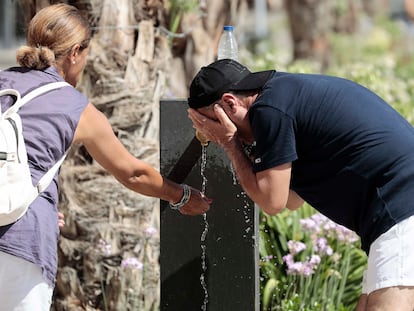 Dos personas se refrescan en una fuente del centro de Valencia en agosto del año pasado durante una de las olas de calor.
