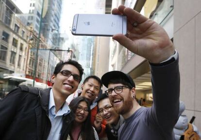 Un empleado de Apple posa para un selfi con varios clientes con un iPhone 6S mientras esperan una cola en la tienda Apple en Sídney (Australia).