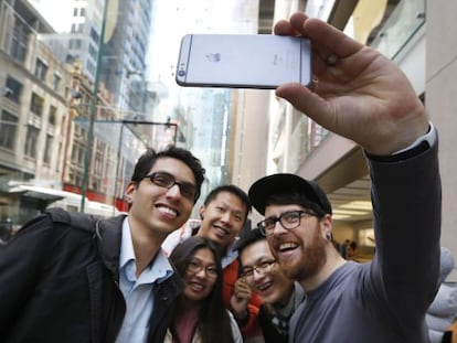 Un empleado de Apple posa para un selfi con varios clientes con un iPhone 6S mientras esperan una cola en la tienda Apple en Sídney (Australia).