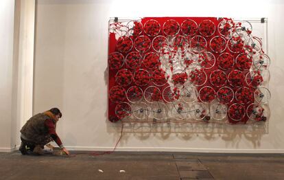 La artista cubana Mabel Poblet junto a su instalación realizada con ruedas y flores en la galería Raquel Ponce.