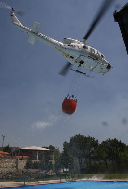 Un helicpótero toma agua de una piscina para lanzarla sobre uno de los focos del fuego declarado en Ávila.