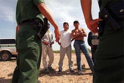 Dos policas de fronteras estadounidenses custodian a un grupo de inmigrantes ilegales mexicanos en Tejas.