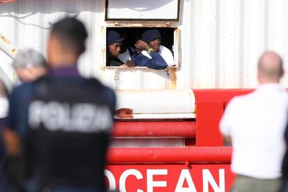 Dos migrantes miran por la ventana del barco de rescate 'Ocean Viking' al llegar al puerto italiano de Messina, el martes.