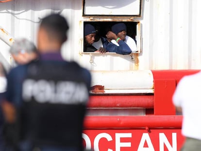 Dos migrantes miran por la ventana del barco de rescate 'Ocean Viking' al llegar al puerto italiano de Messina, el martes.
