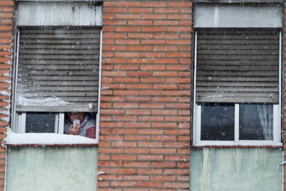 Una mujer toma fotografías desde la ventana de su casa, durante la nevada provocada por la borrasca 'Filomena', en Madrid.