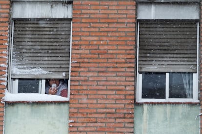 Una mujer toma fotografías desde la ventana de su casa, durante la nevada provocada por la borrasca 'Filomena', en Madrid.