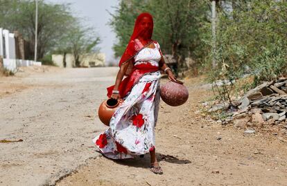 Una mujer carga con ollas de barro para llenarlas con agua potable a las afueras de Ajmer, en el Estado de Rayastán (India).