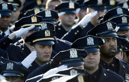 Agentes hacen el saludo oficial mientras suena el himno nacional de EE UU en el exterior de la iglesia que ha acogido el funeral por el policía Rafael Ramos en el distrito de Queens.