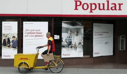 Un repartidor pasa ante una oficina del Banco Popular. EFE/Archivo