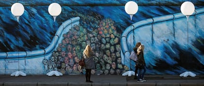 Algunas personas caminan por debajo de unos globos colocados en el muro de Berlín, mobiliario que se usó en la instalación 'Lichtgrenze' (Alemania), el 7 de noviembre de 2014.