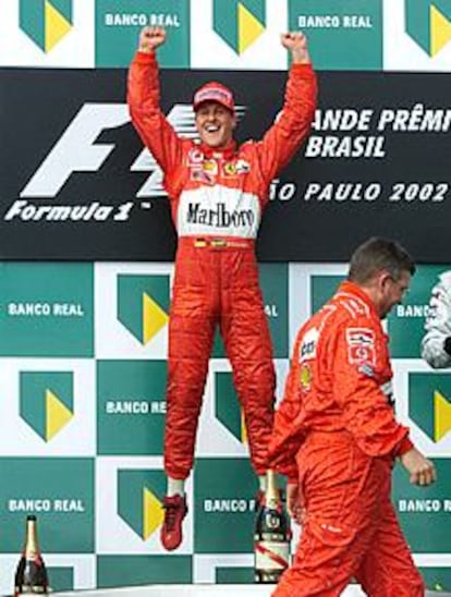 Michael Schumacher celebra en el podio su victoria ante el director técnico de su equipo, Ross Brawn.