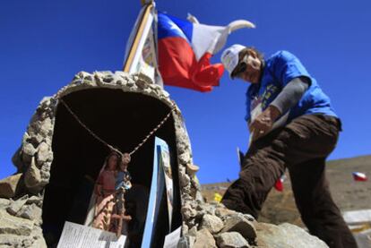 Un familiar de uno de los mineros atrapados junto a un altar levantado con piedras cerca de la mina de San José.