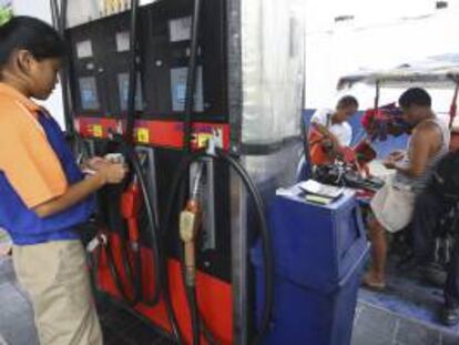La trabajadora de una gasolinera cuenta dinero junto a un surtidor en una gasolinera en Quezon (Filipinas). EFE/Archivo