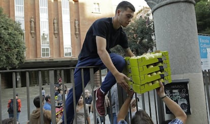 Un hombre ayuda a cargar cajas dentro del colegio de primaria Collaso i Gil, una de los colegios electorales designados para el refer&eacute;ndum.