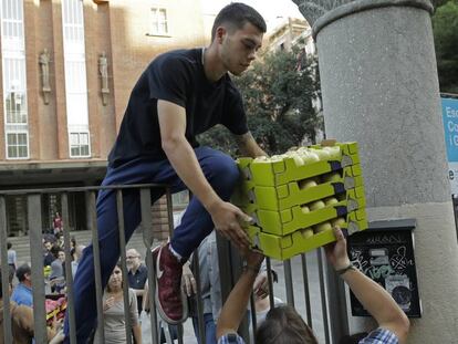 Un hombre ayuda a cargar cajas dentro del colegio de primaria Collaso i Gil, una de los colegios electorales designados para el refer&eacute;ndum.