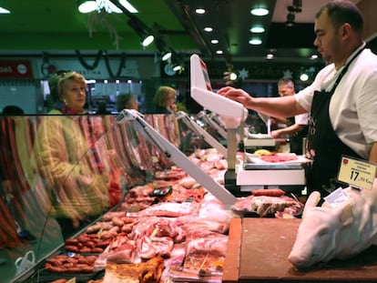 Un carnicero atiende a sus clientes en un mercado de Madrid.
