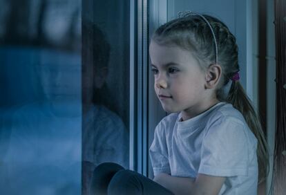 Una niña piensa apoyada en la ventana.