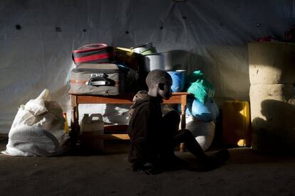 Daniel Kampa, de 8 años, permanece sentado junto a su equipaje en una tienda comunitaria del campo de tránsito de Kuluba, a la espera de ser trasladado al campo de refugiados de Imvepi.