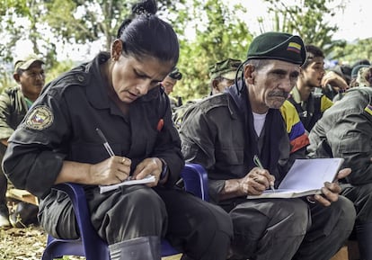 TO GO WITH AFP STORY by Hector Velasco
Cornelio (R), a member of the Revolutionary Armed Forces of Colombia (FARC), takes notes during a "class" on the peace process between the Colombian government and their force, at a camp in the Colombian mountains on February 18, 2016. They still wear green combat fatigues and carry rifles and machetes, but now FARC rebel troops are sitting down in the jungle to receive "classes" on how life will be when they lay down their arms, if their leaders sign a peace deal in March as hoped.  AFP PHOTO / LUIS ACOSTA