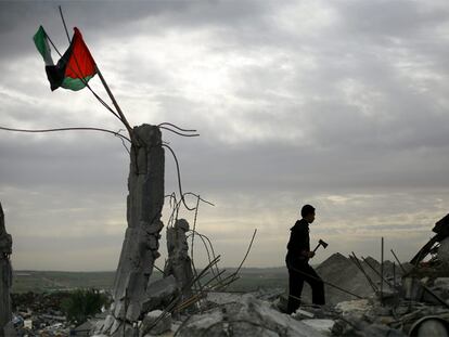 Un joven camina entre las ruinas de una casa bombardeada en el norte de Gaza en la que ondea una bandera palestina.