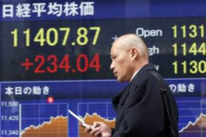 Un viandante pasa delante de un panel electrónico que muestra el valor alcanzado por el índice Nikkei de la Bolsa de Tokio. EFE/Archivo
