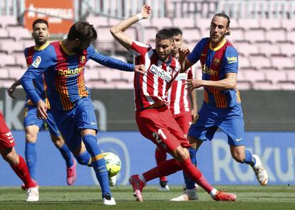 El atlético Yannick Carrasco (en el centro) lucha por la pelota con el defensa del Barcelona Gerard Piqué.