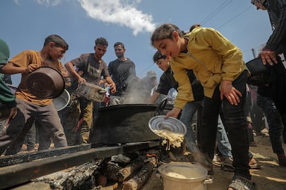 Desplazados palestinos reciben su porción de comida de una olla que ha sido cocinada con madera, este viernes en Yabalia, en el norte de Gaza.