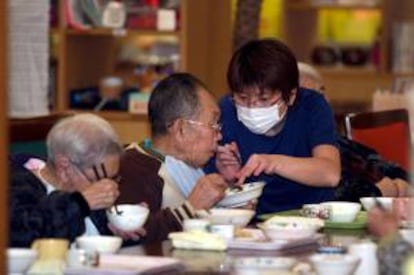 Una empleada ayuda a comer a un anciano en una residencia para ancianos japonesa.