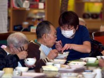 Una empleada ayuda a comer a un anciano en una residencia para ancianos japonesa.