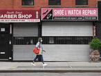 (FILES) In this file photo taken on May 5, 2020, a woman walks by a closed barber shop and shoe and watch repair store in the Brooklyn borough of New York City. - Lockdown measures in New York City have been extended until June 13 under an executive order signed by state Governor Andrew Cuomo late May 14, 2020. Stay at home orders will be eased for the state's five least populated regions, however, allowing businesses there to get back to work gradually. (Photo by Angela Weiss / AFP)