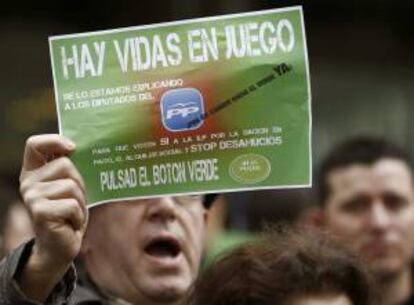 Un hombre sostiene un cartel con el lema "Hay vidas en juego" durante la concentración convocada por la Plataforma de Afectados por la Hipoteca (PAH-HUT). EFE/Archivo
