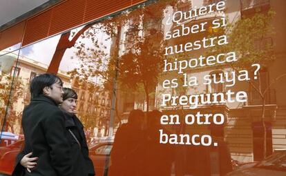 Una pareja lee un cartel sobre hipotecas en una sucursal.