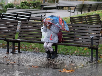 Una niña protegida con un paraguas merienda en la plaza de Europa, en Gijón, el pasado 1 de diciembre.